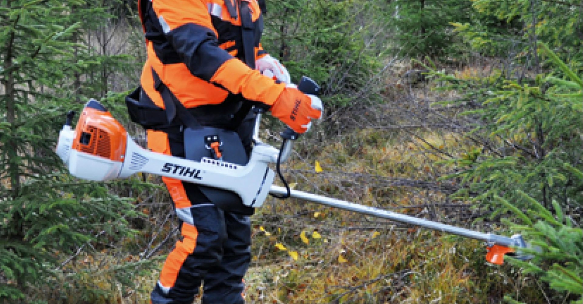 Person i säkerhetsutrustning som använder en Stihl röjsax i ett skogsområde.